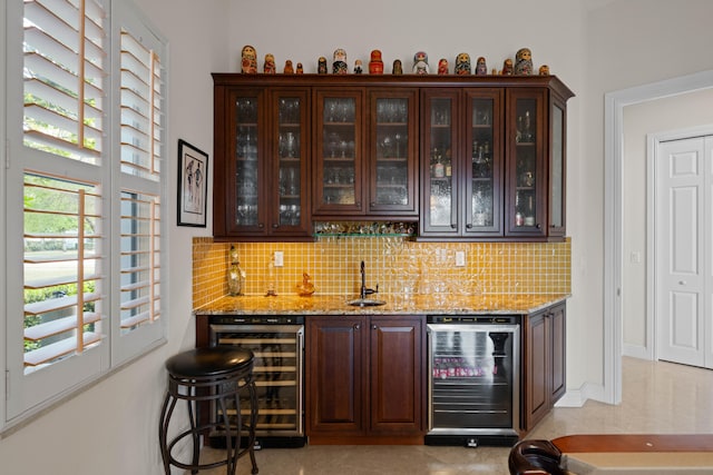 bar featuring wine cooler, tasteful backsplash, sink, and light stone countertops