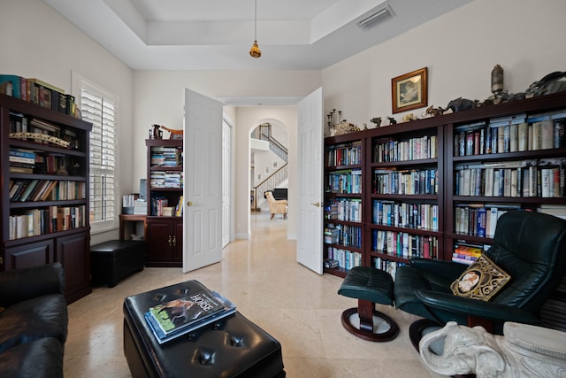 living area featuring a raised ceiling and light tile flooring