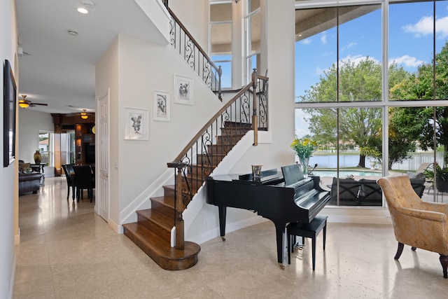 miscellaneous room featuring tile flooring, ceiling fan, and a high ceiling