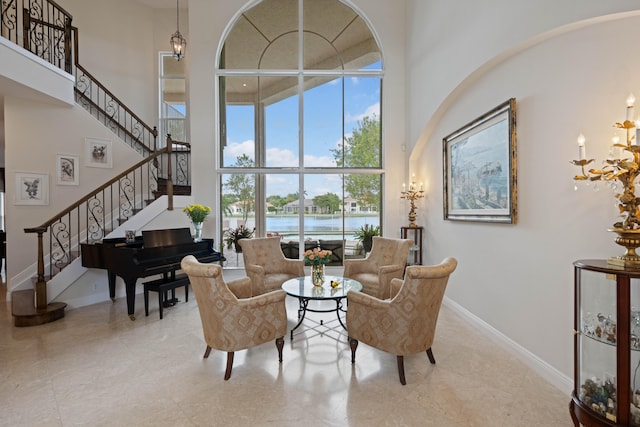 sitting room with light tile floors, a high ceiling, and a water view