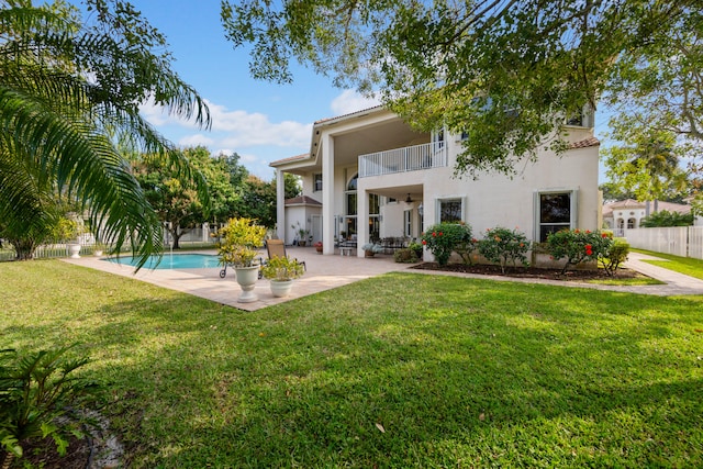 rear view of house featuring a balcony, a patio area, a lawn, and a fenced in pool