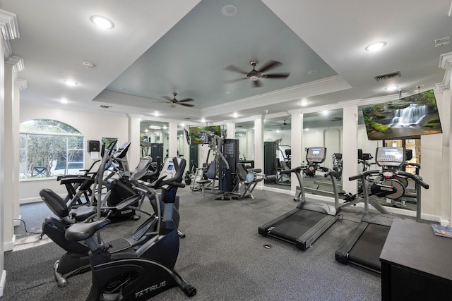 gym with ornamental molding, ceiling fan, carpet flooring, and a raised ceiling