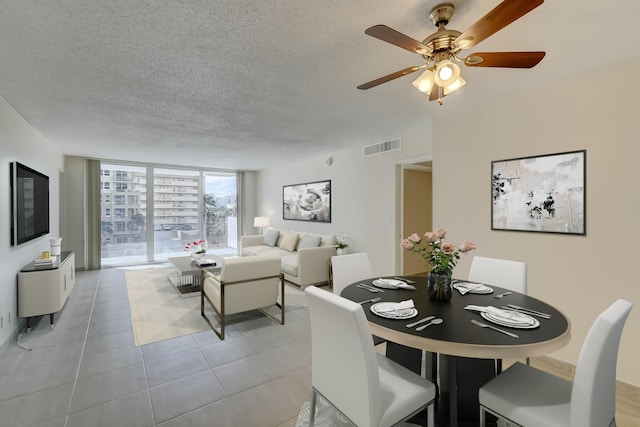 dining area with light tile floors, a textured ceiling, a wall of windows, and ceiling fan