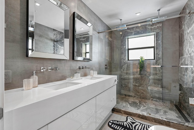 bathroom with an enclosed shower, double sink vanity, and tile walls