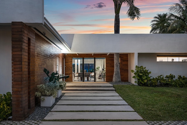 exterior entry at dusk with a lawn