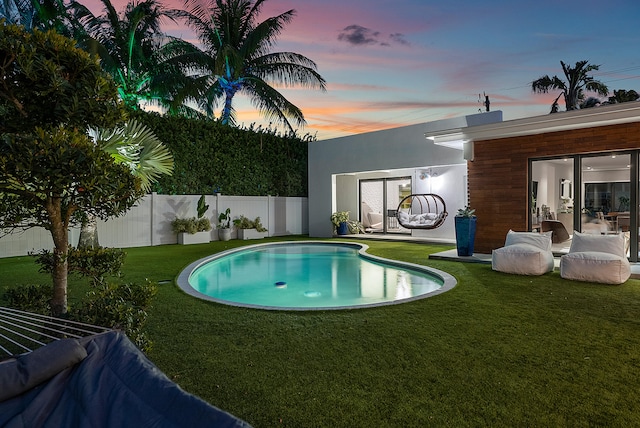 pool at dusk with a lawn and a patio