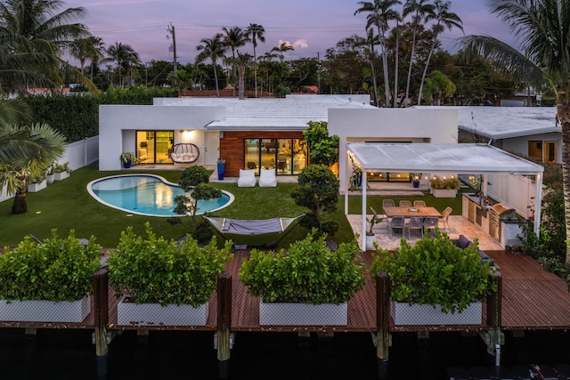 back house at dusk featuring a lawn, outdoor lounge area, and a patio