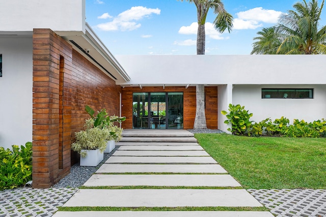 view of exterior entry with a yard