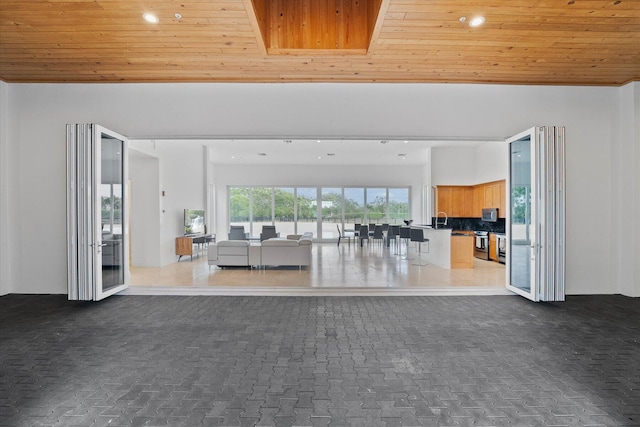 unfurnished living room with wood ceiling, tile floors, and sink