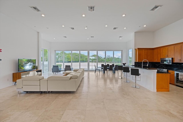 tiled living room featuring sink and a towering ceiling