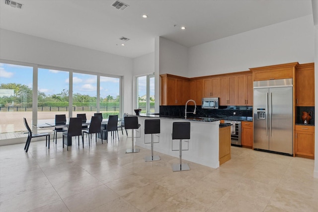 kitchen with backsplash, stainless steel appliances, a kitchen bar, and light tile floors