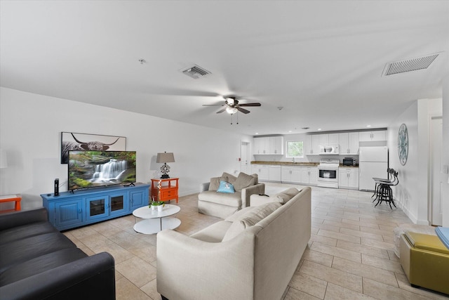 living room with light tile flooring, ceiling fan, and sink