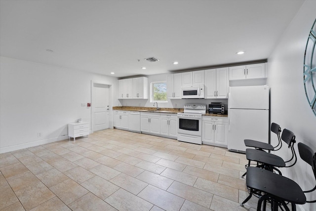 kitchen with white appliances, light tile flooring, and white cabinets