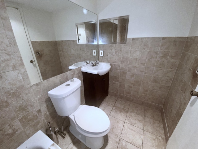 bathroom featuring vanity, toilet, tile walls, and a bath