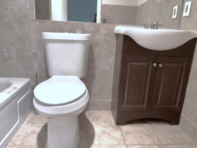 bathroom with toilet, vanity, tile walls, and tile patterned flooring