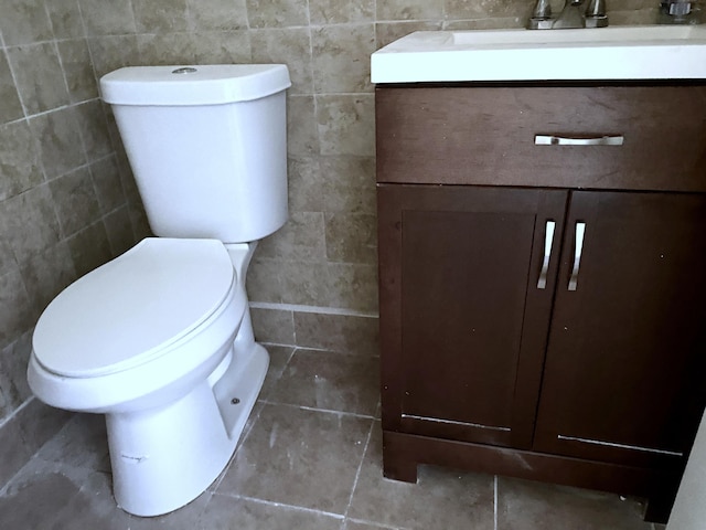 bathroom with toilet, vanity, and tile walls