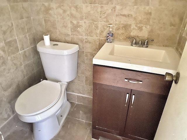 bathroom featuring vanity, toilet, and tile walls