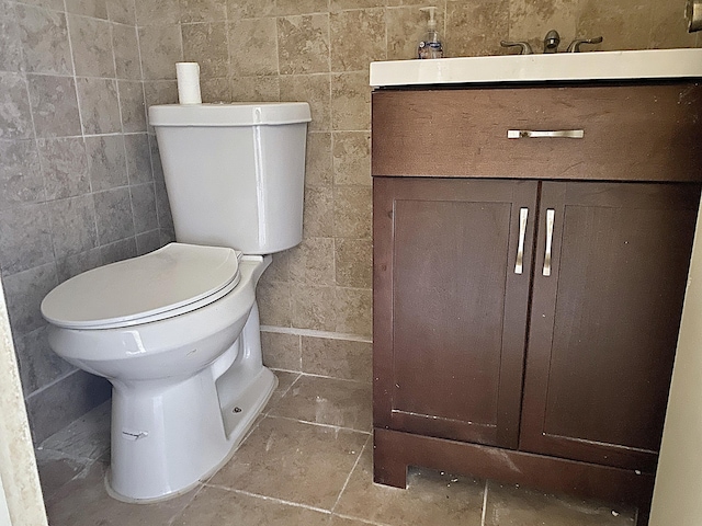 bathroom with toilet, vanity, and tile walls