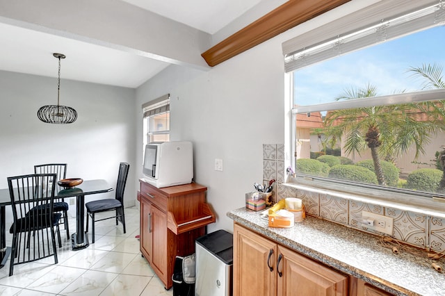 kitchen with light tile floors, hanging light fixtures, and a healthy amount of sunlight