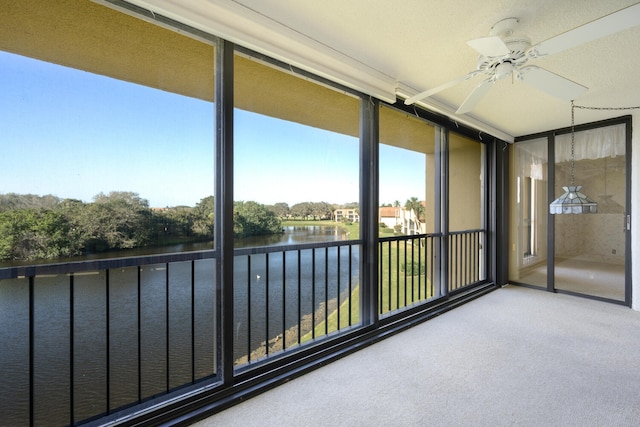 unfurnished sunroom with plenty of natural light, a water view, and ceiling fan