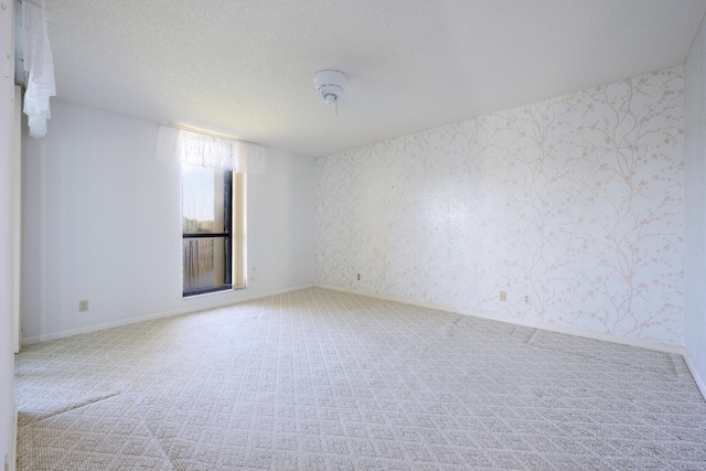 empty room with light carpet and a textured ceiling