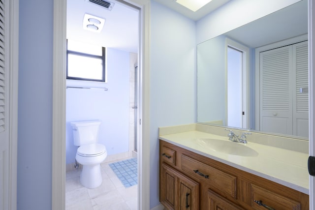 bathroom with toilet, vanity, and tile flooring