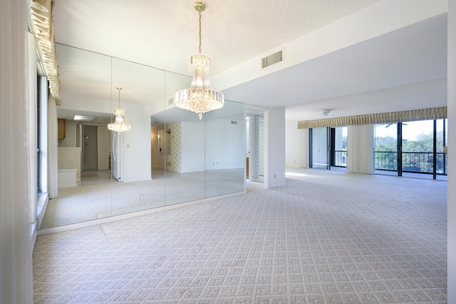 empty room featuring an inviting chandelier, light carpet, and a textured ceiling