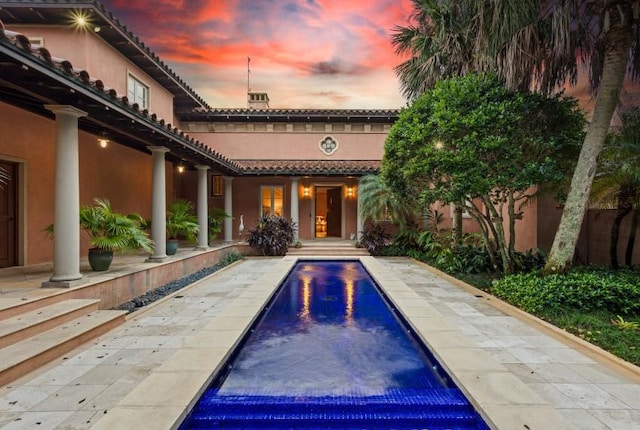 pool at dusk with a patio area