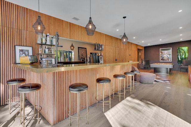 bar with hanging light fixtures and light hardwood / wood-style floors