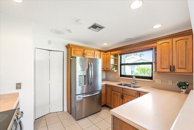 kitchen with a textured ceiling, sink, appliances with stainless steel finishes, and light tile patterned flooring