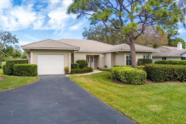 ranch-style house featuring a garage and a front lawn