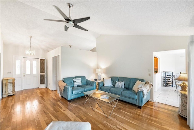 living room featuring a textured ceiling, ceiling fan with notable chandelier, hardwood / wood-style floors, and lofted ceiling