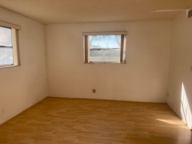 unfurnished room with a textured ceiling and light hardwood / wood-style flooring