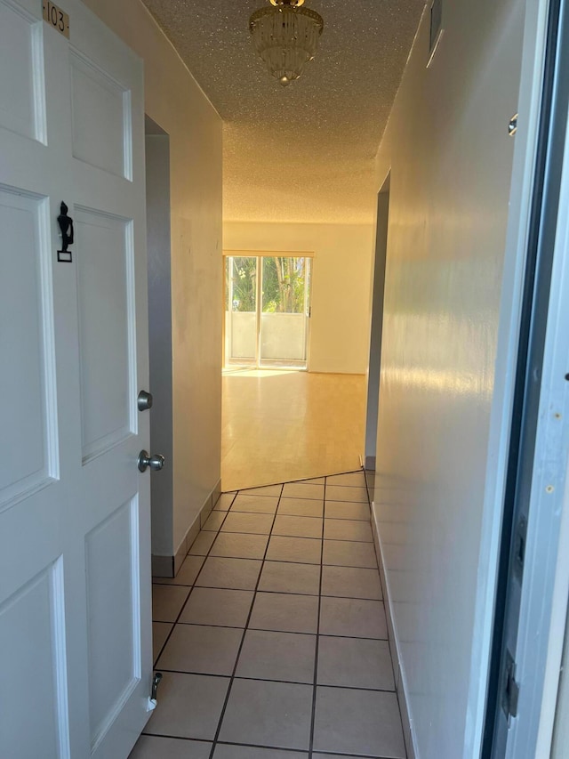 corridor featuring light tile floors and a textured ceiling