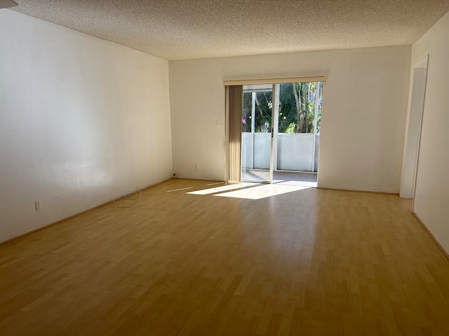 unfurnished room featuring light hardwood / wood-style flooring and a textured ceiling