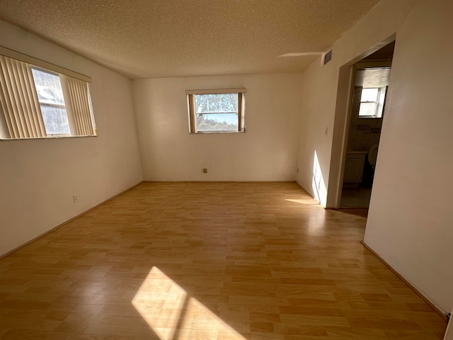 unfurnished room with a textured ceiling and light wood-type flooring