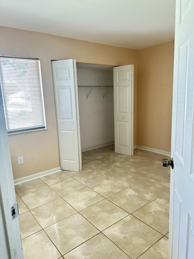 unfurnished bedroom with light tile patterned floors and a closet