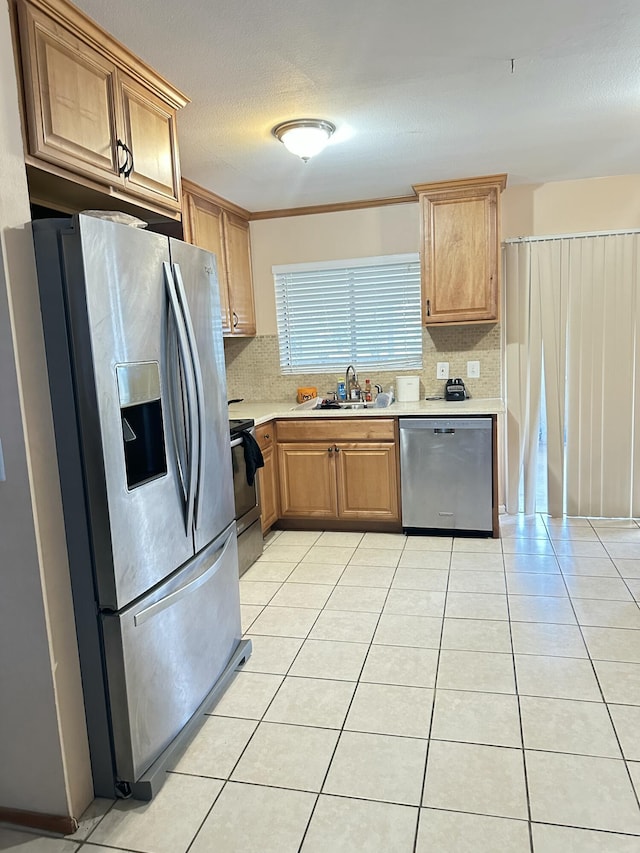 kitchen featuring backsplash, sink, light tile patterned flooring, and stainless steel appliances