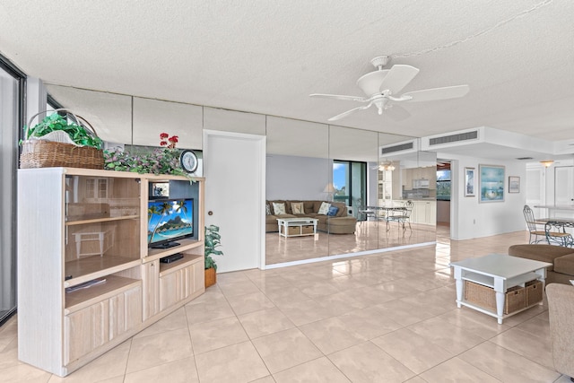 living room featuring light tile floors, ceiling fan, and a textured ceiling