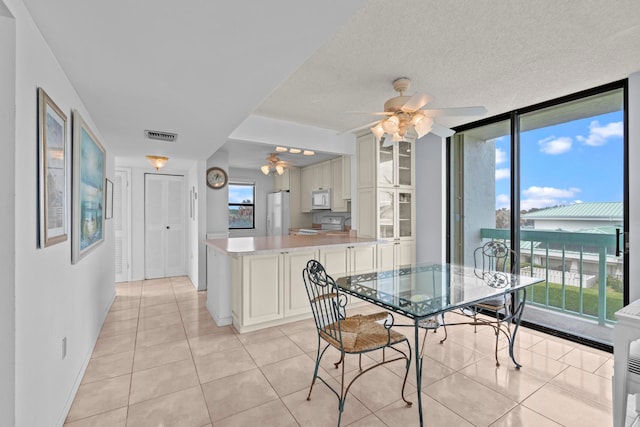 tiled dining space with a textured ceiling and ceiling fan