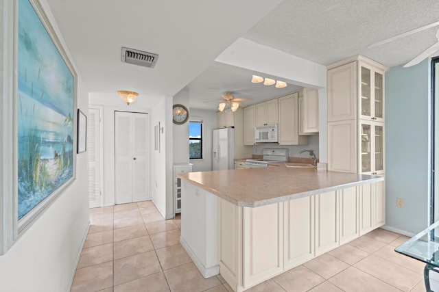 kitchen with light tile floors, ceiling fan, kitchen peninsula, white appliances, and sink