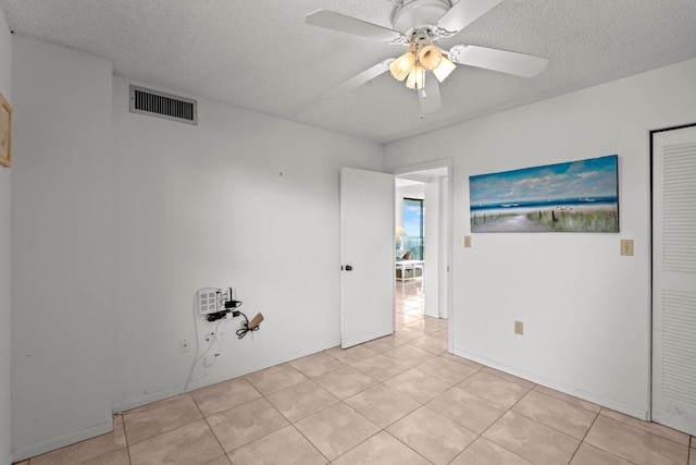 tiled empty room featuring a textured ceiling and ceiling fan