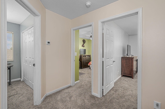 corridor featuring light carpet and a textured ceiling