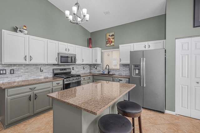 kitchen featuring a center island, hanging light fixtures, high vaulted ceiling, gray cabinets, and appliances with stainless steel finishes