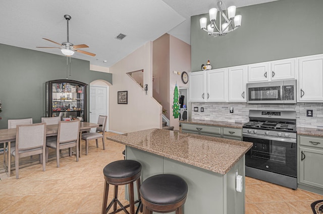 kitchen with light stone countertops, a center island, hanging light fixtures, stainless steel appliances, and decorative backsplash