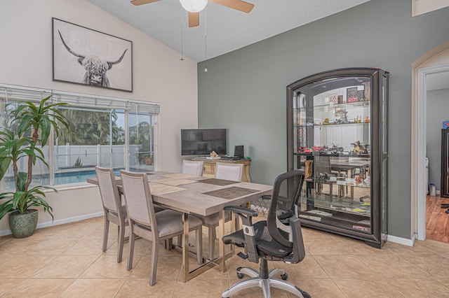 tiled dining area with ceiling fan and lofted ceiling