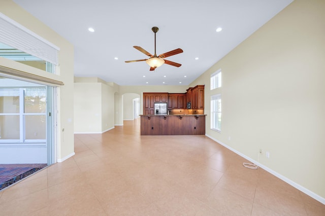 unfurnished living room featuring light tile floors and ceiling fan