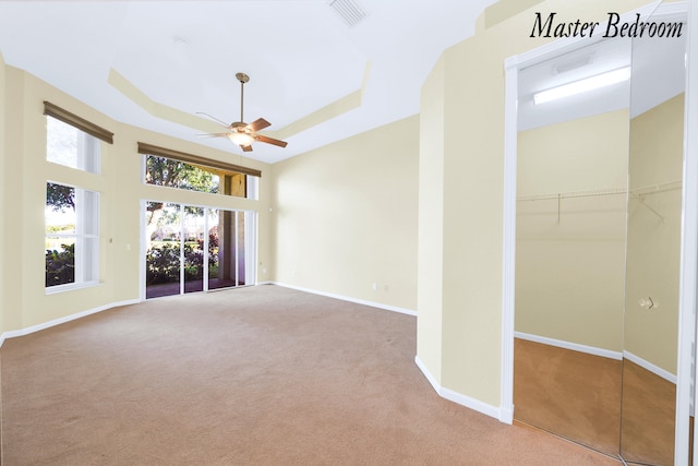 interior space with a tray ceiling, ceiling fan, and light colored carpet