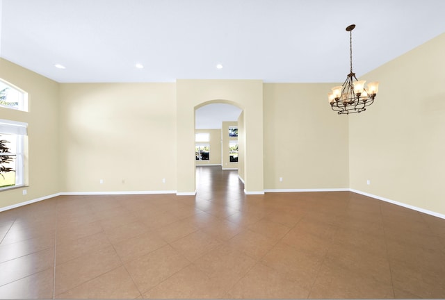 tiled spare room with a chandelier