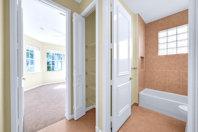 bathroom with tiled shower / bath, toilet, and tile floors